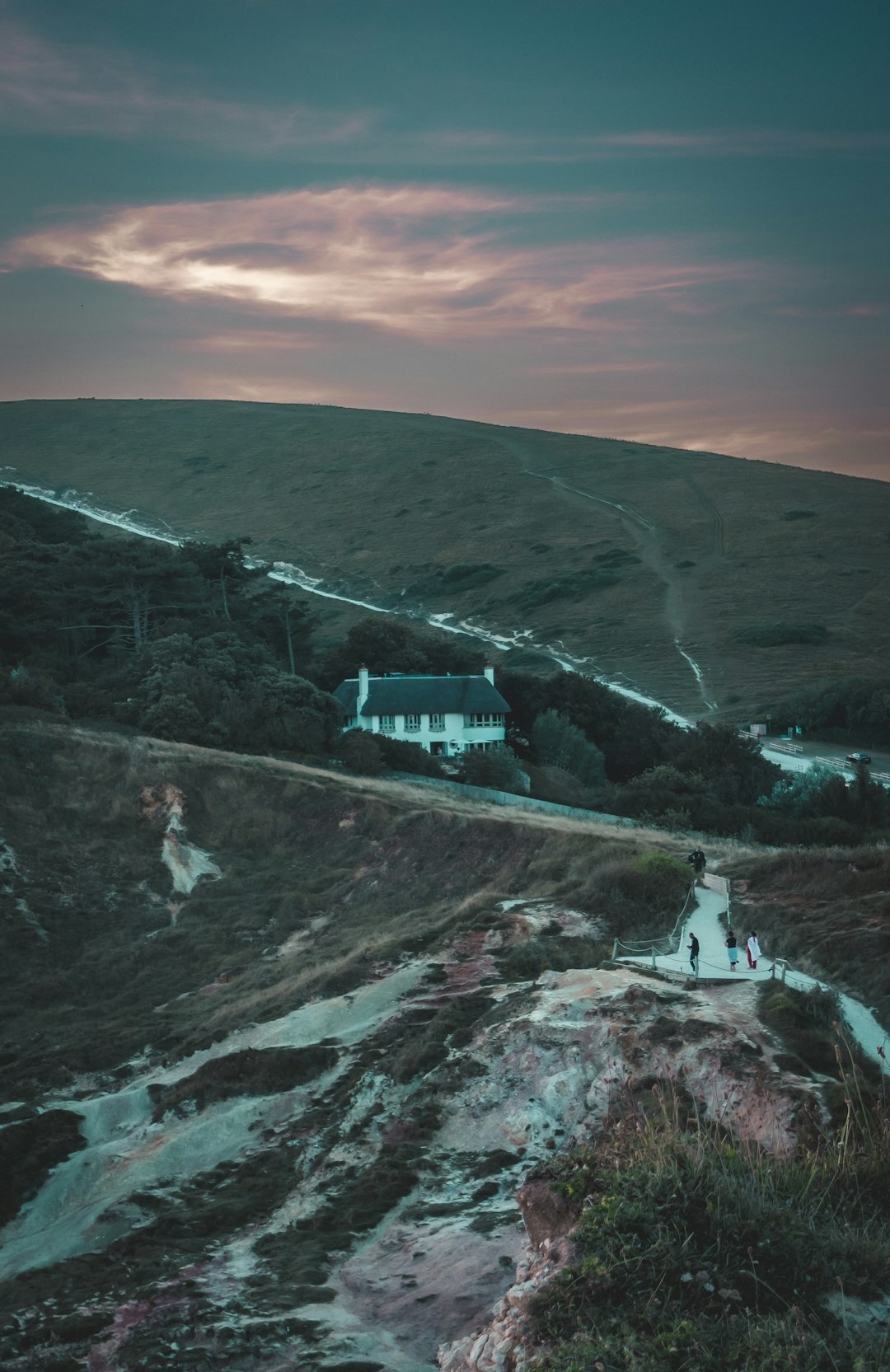 Dark book cover illustration of an old house on a cliff at dusk